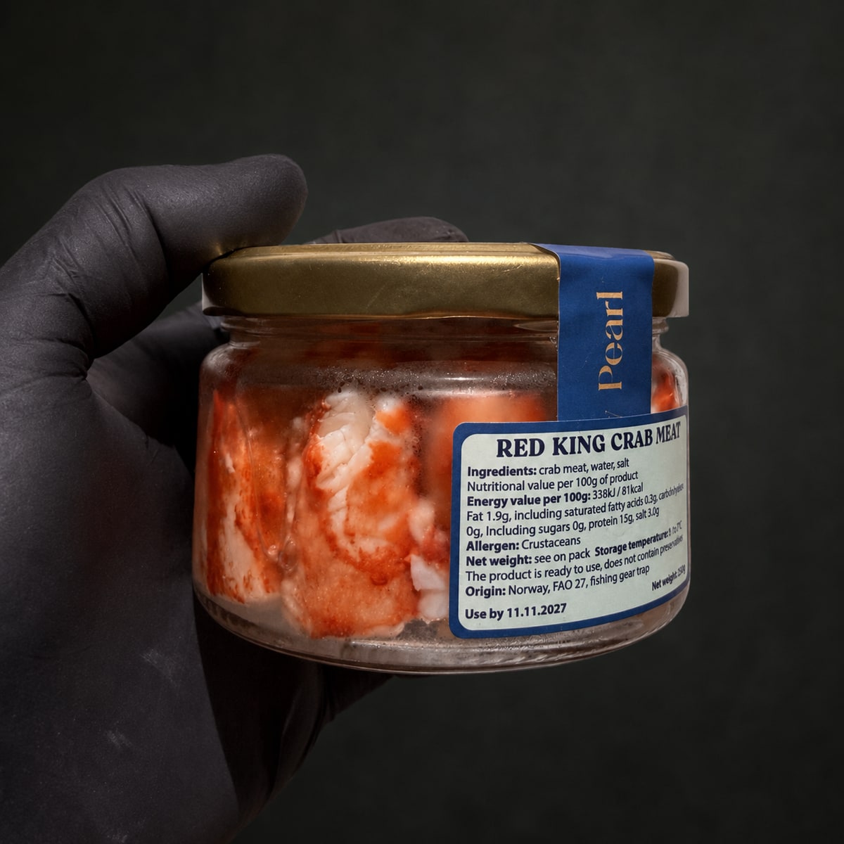 Банка натурального м’яса Red King Crab Norway Pearl 250 г у руці на графітовому фоні